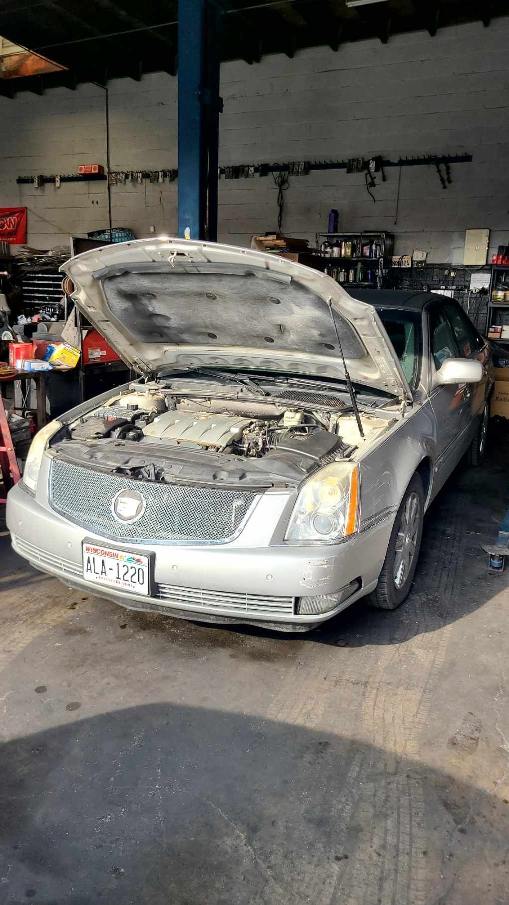 A car with the hood up is sitting in a garage.