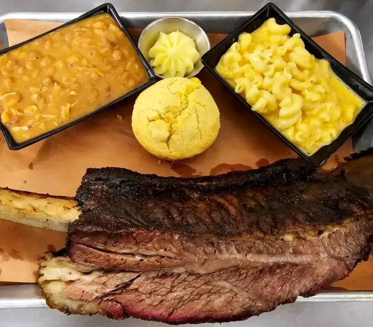 Pulled pork sandwich with barbecue sauce and a small cup of sauce on the side