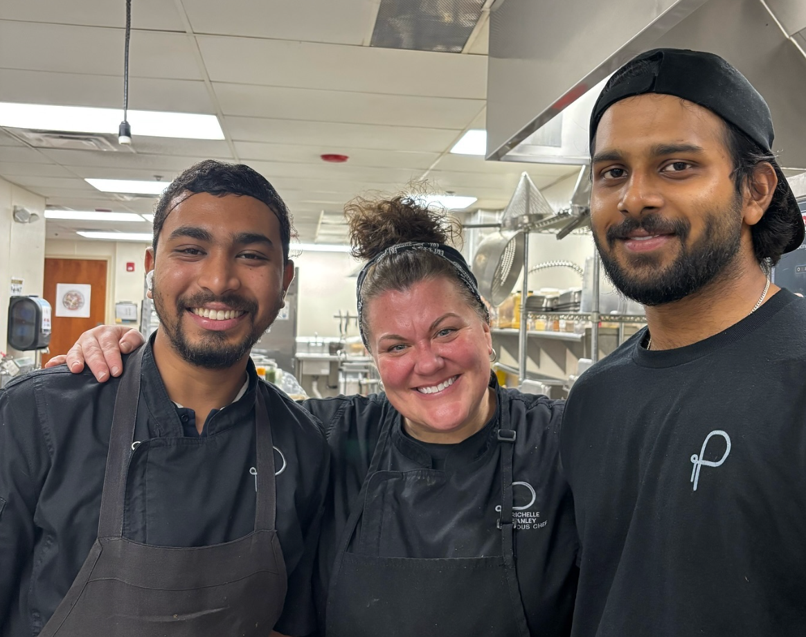 A man in a chef 's hat is posing for a picture with two other chefs