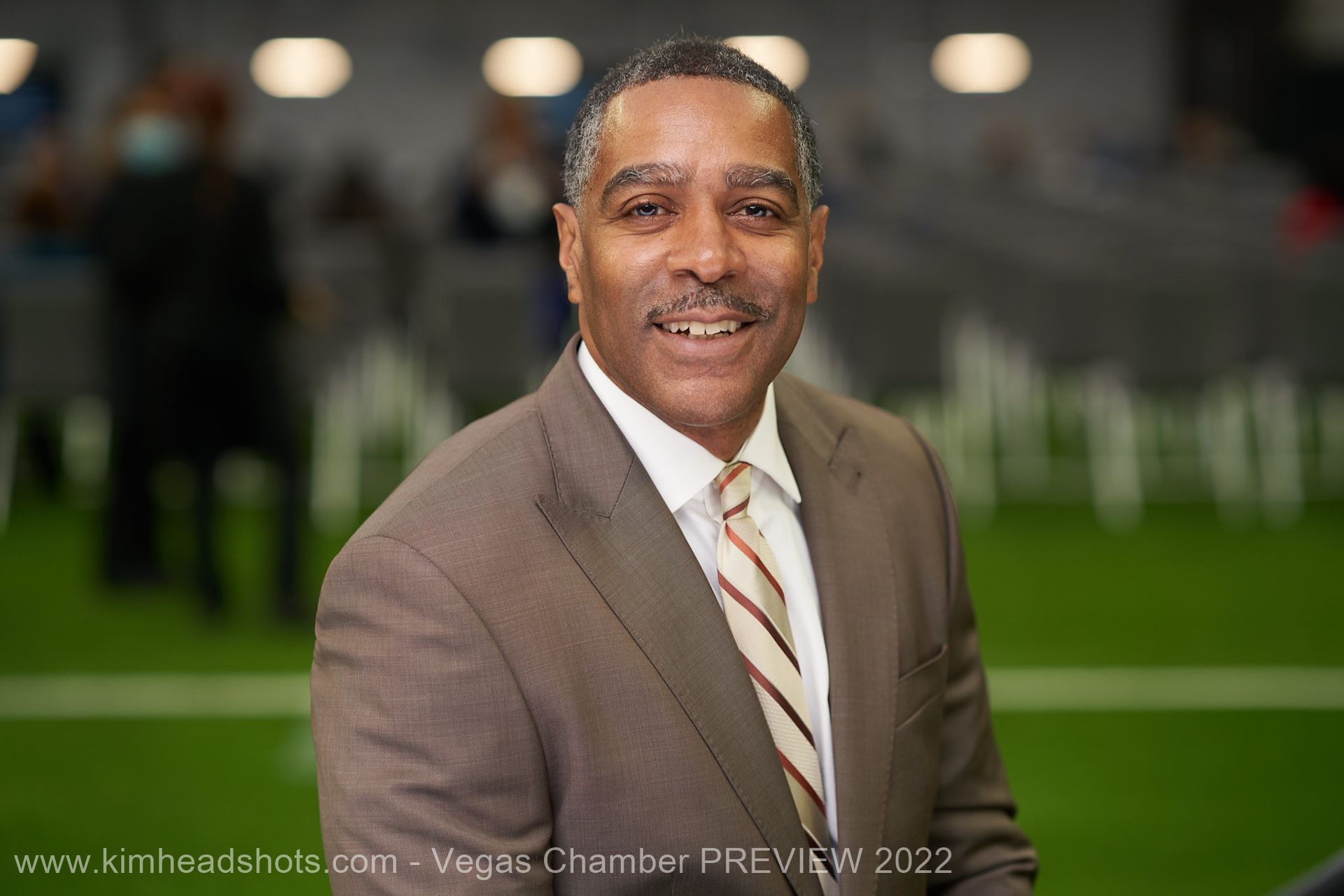 Man in suit and glasses smiling, close-up.