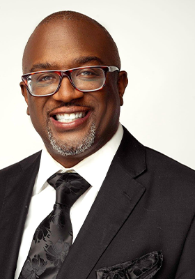 Man in suit and glasses smiling, close-up.