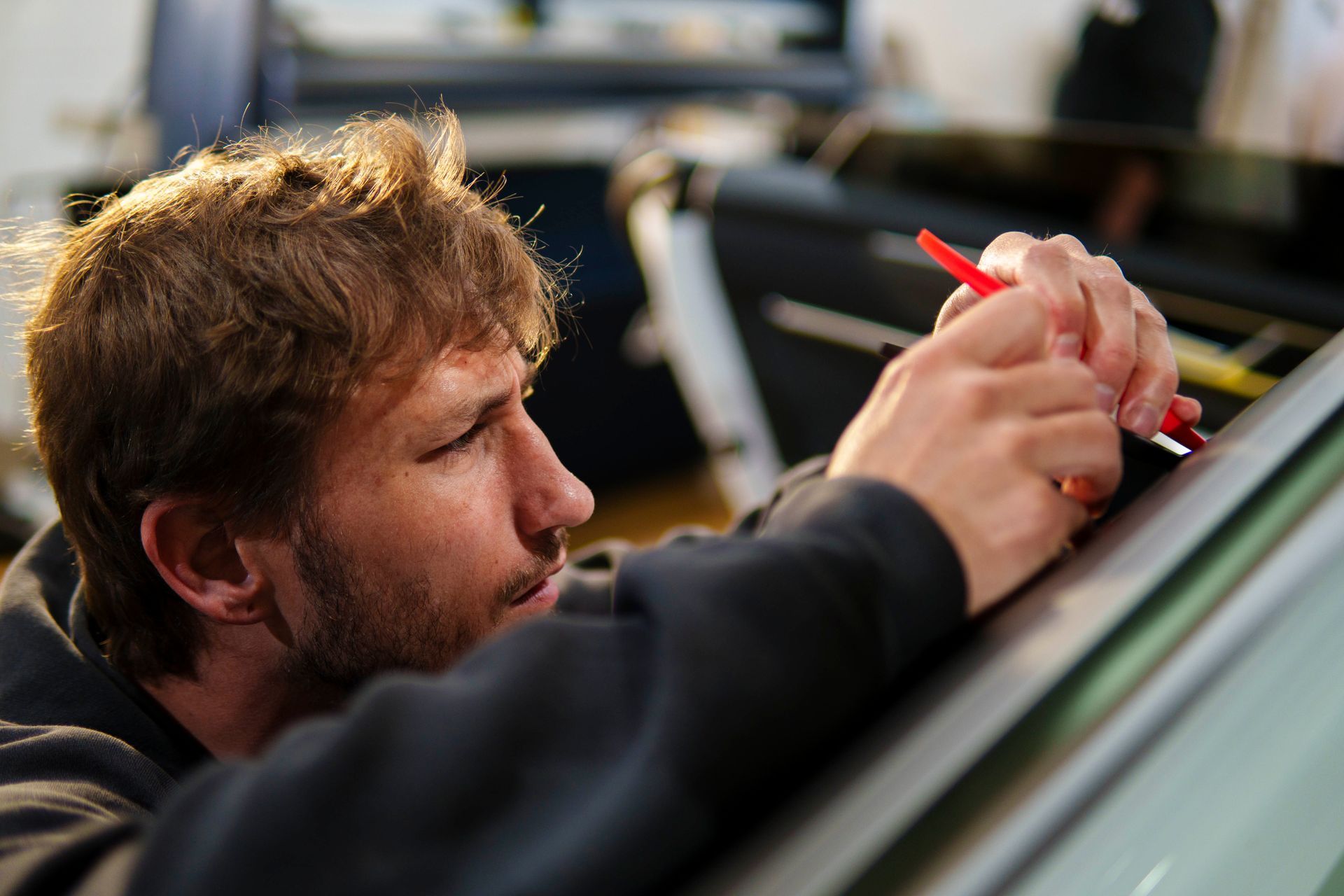 A man is working on a car with a red marker