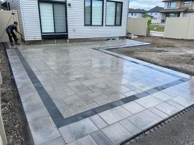 Un homme se tient debout sur une terrasse devant une maison.