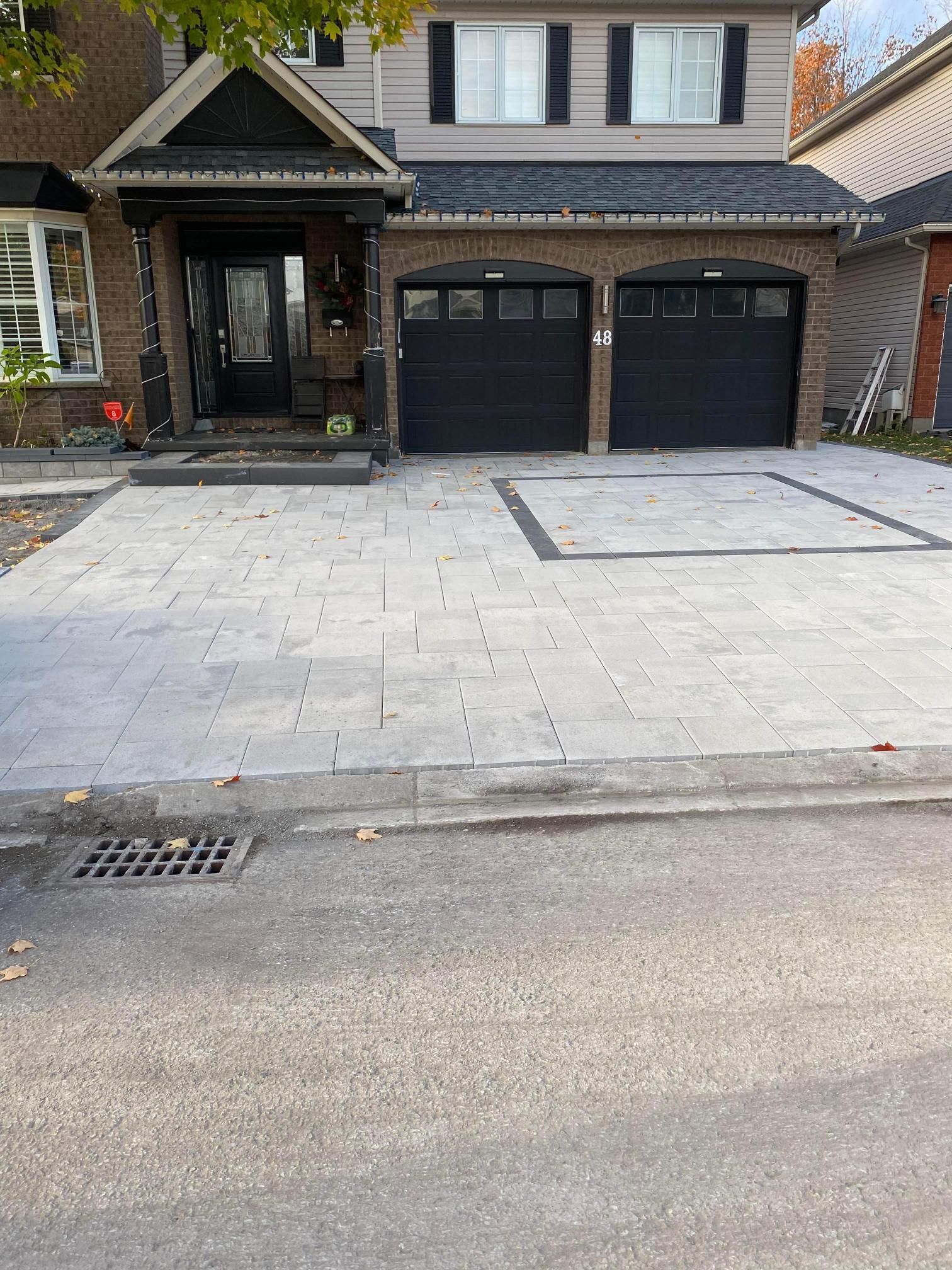 Une maison avec deux portes de garage et une allée devant.