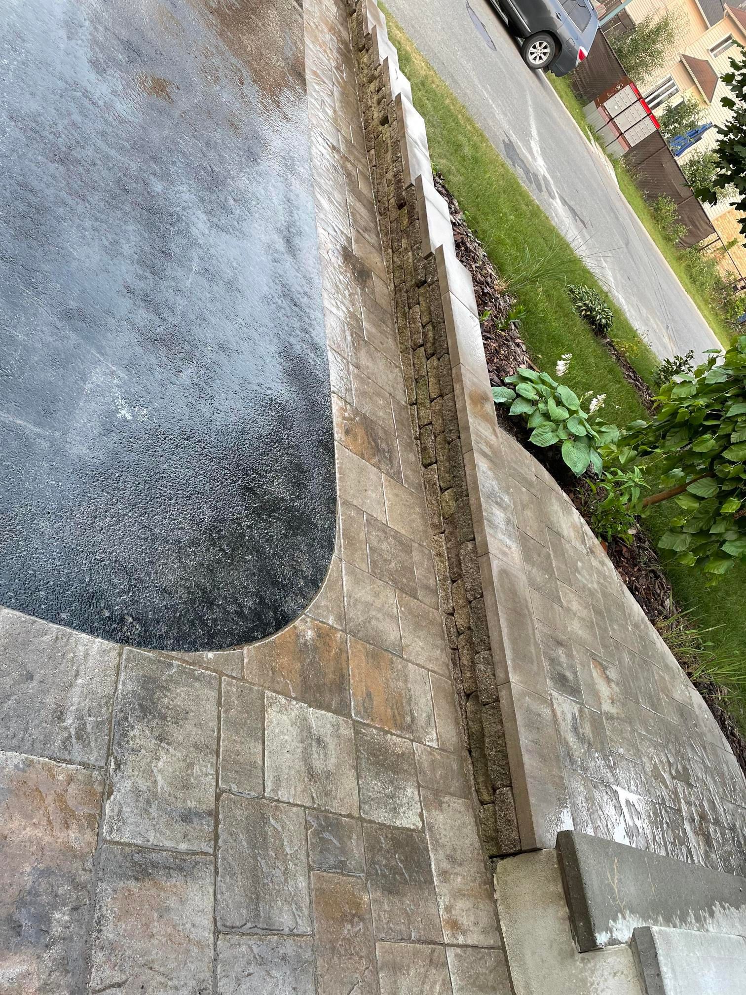 Une personne se tient sur un trottoir à côté d'un mur.