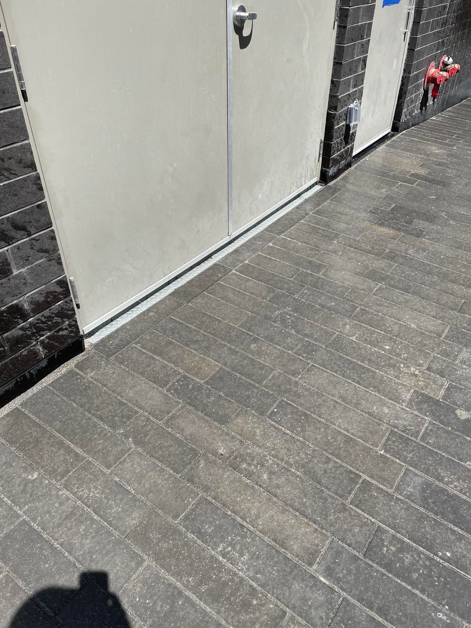 L'ombre d'une personne est projetée sur un sol en brique à côté d'une porte.