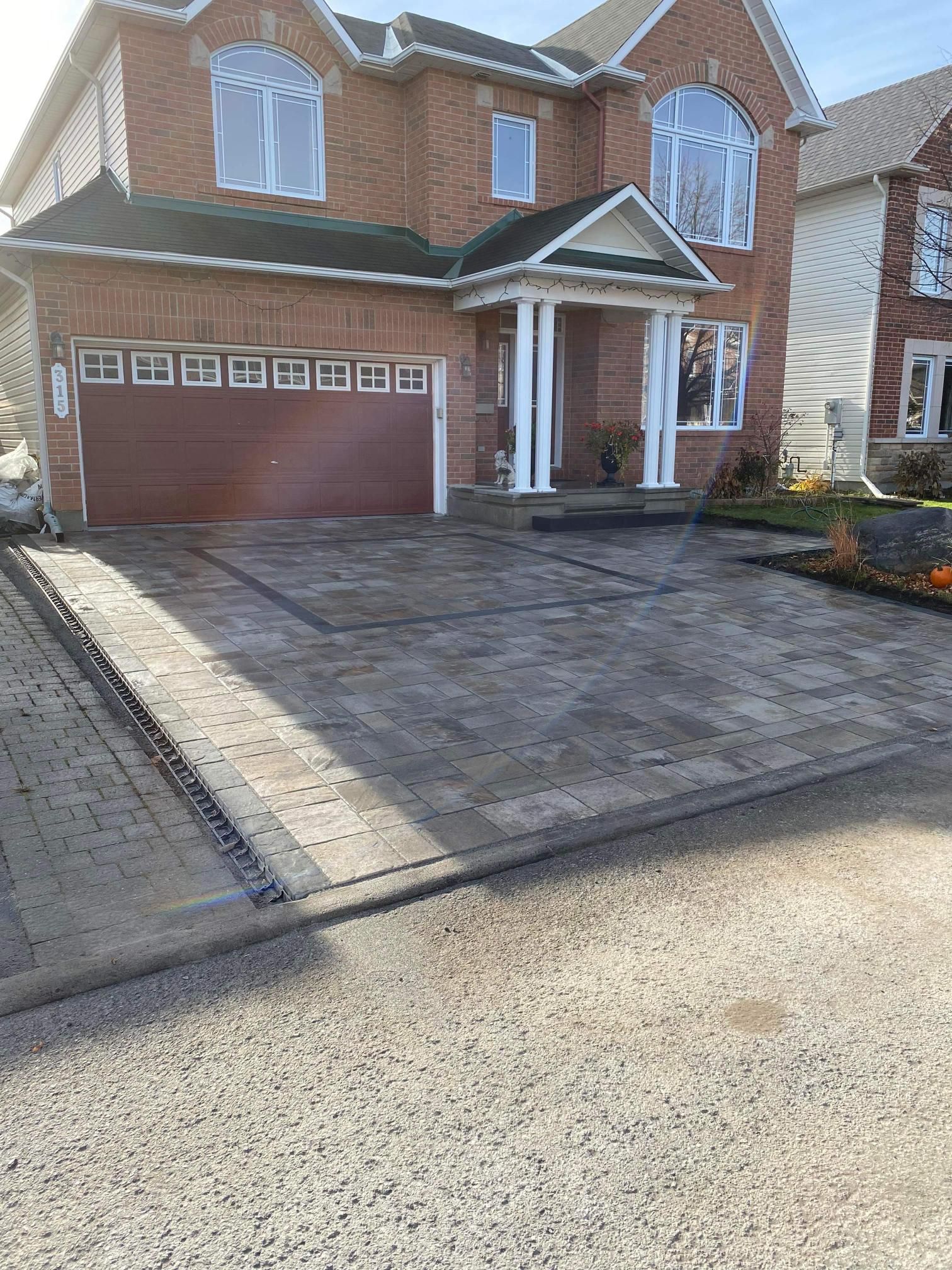 Une grande maison en brique avec une grande allée devant.