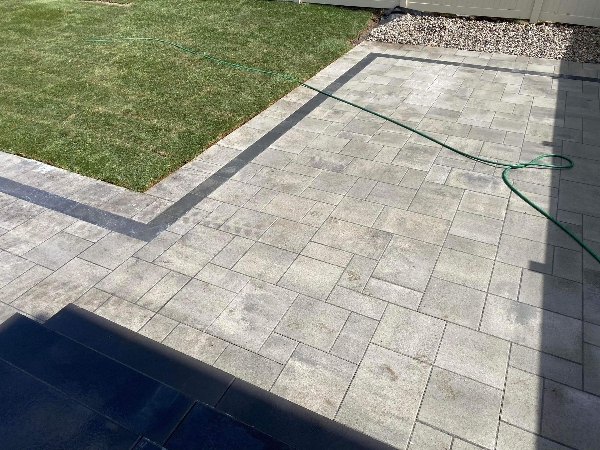 Un patio avec un tuyau qui y est attaché et une pelouse en arrière-plan.