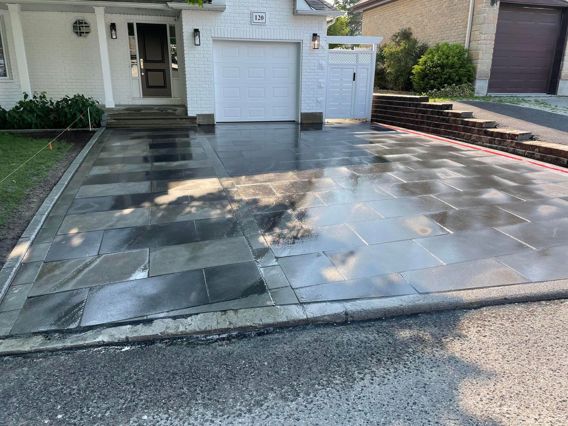 Une allée devant une maison avec une porte de garage blanche.