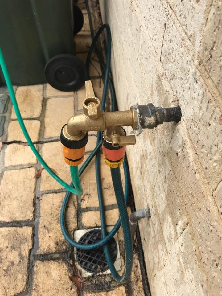 Brass Outdoor Water Tap With Two Attached Green Hoses — Hunter Plumbing And Hotwater in Raymond Terrace, NSW