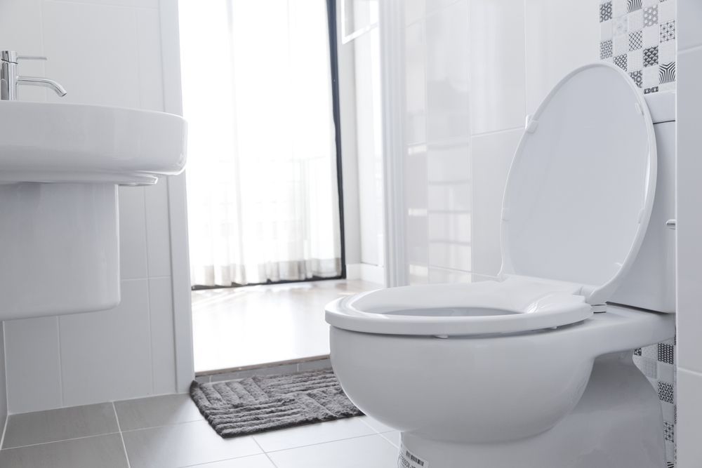 Bright white bathroom with a toilet, sink, and open doorway. 