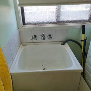 White Utility Sink With Chrome Faucets, Beneath a Window in a Laundry Room — Hunter Plumbing And Hotwater in Medowie, NSW
