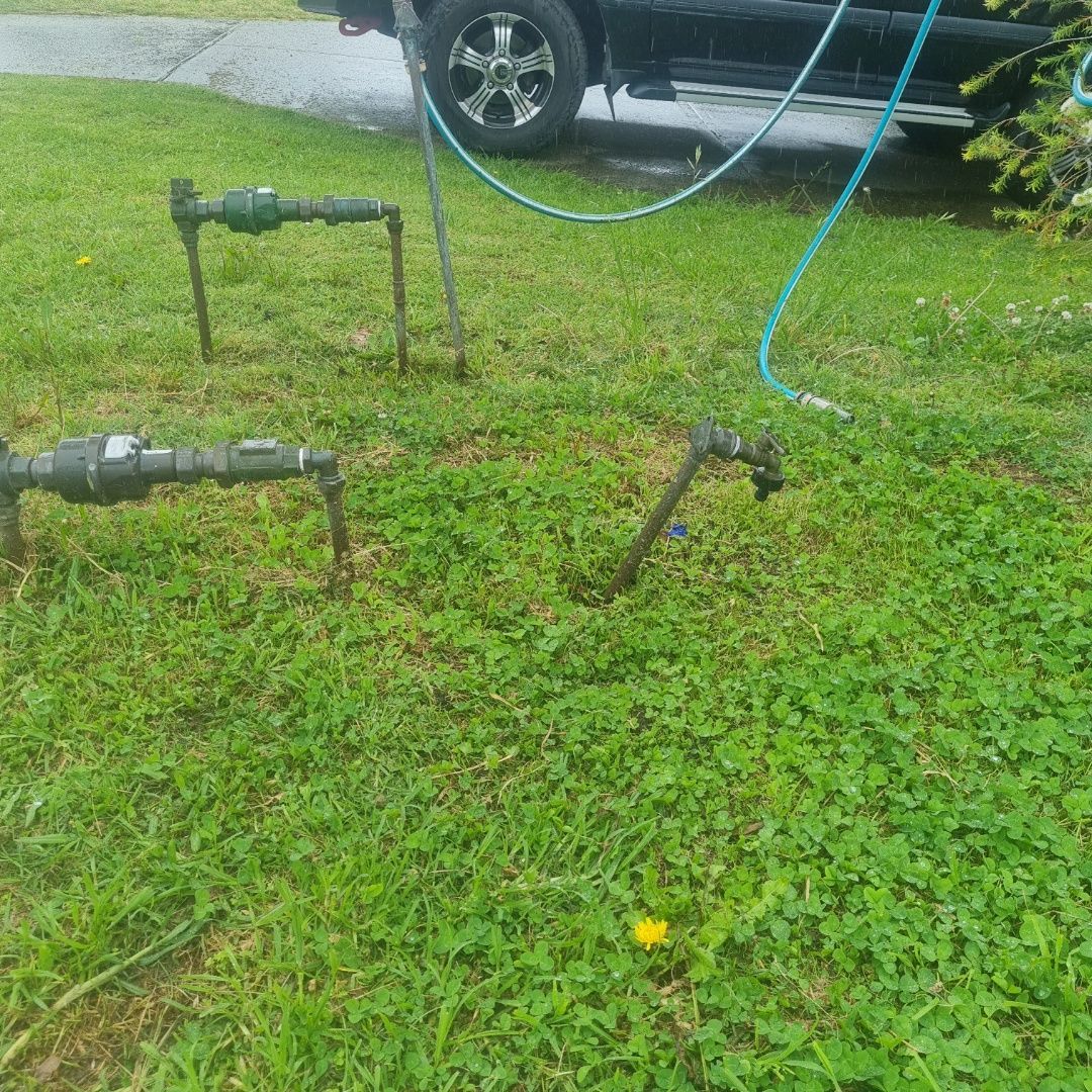 Irrigation System Components Are in Grassy Yard, With a Truck and Hose Nearby — Hunter Plumbing And Hotwater in Medowie, NSW