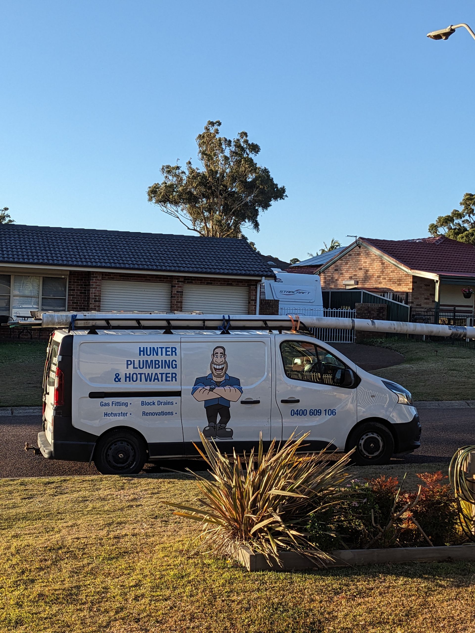 White Plumber's Van Parked on Grass, Logo on Side — Hunter Plumbing And Hotwater in Raymond Terrace, NSW
