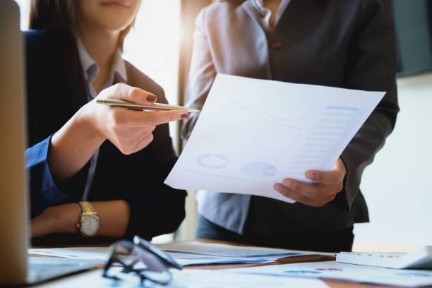 Two professionals reviewing financial charts during a fraud investigation meeting.