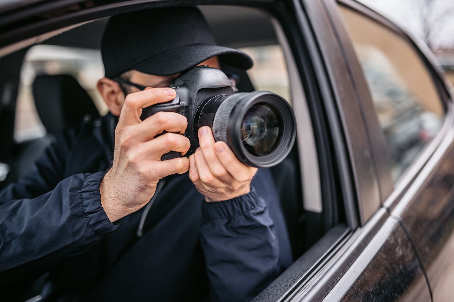 Person taking a photo with a DSLR camera from inside a car window.