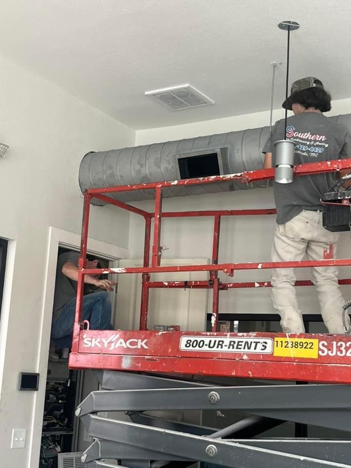 A man is standing on a scissor lift in a room.