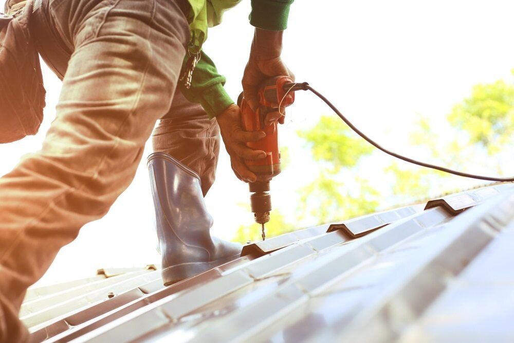 A worker installing a metal roof — Licensed Roofer in Bungendore