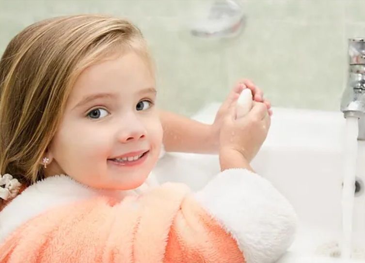 Girl standing at a sink washing her hands