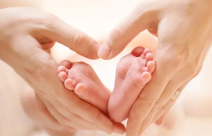 Parents hands cradling a newborn baby's feet