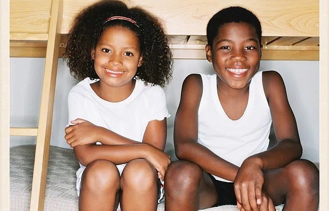 Two smiling, happy children sitting on a bunk bed