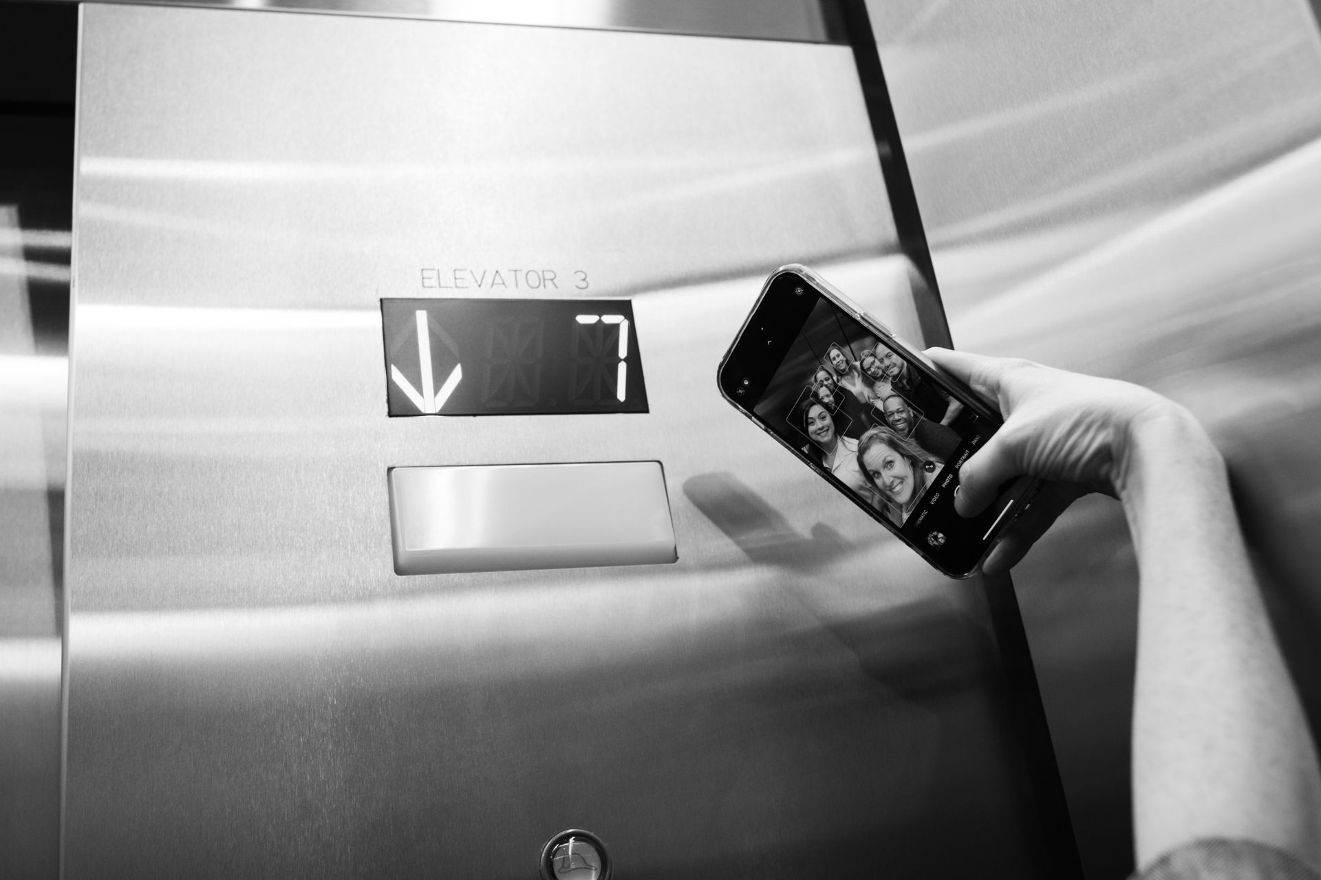 Person holding phone, taking photo of elevator floor indicator, level 7.