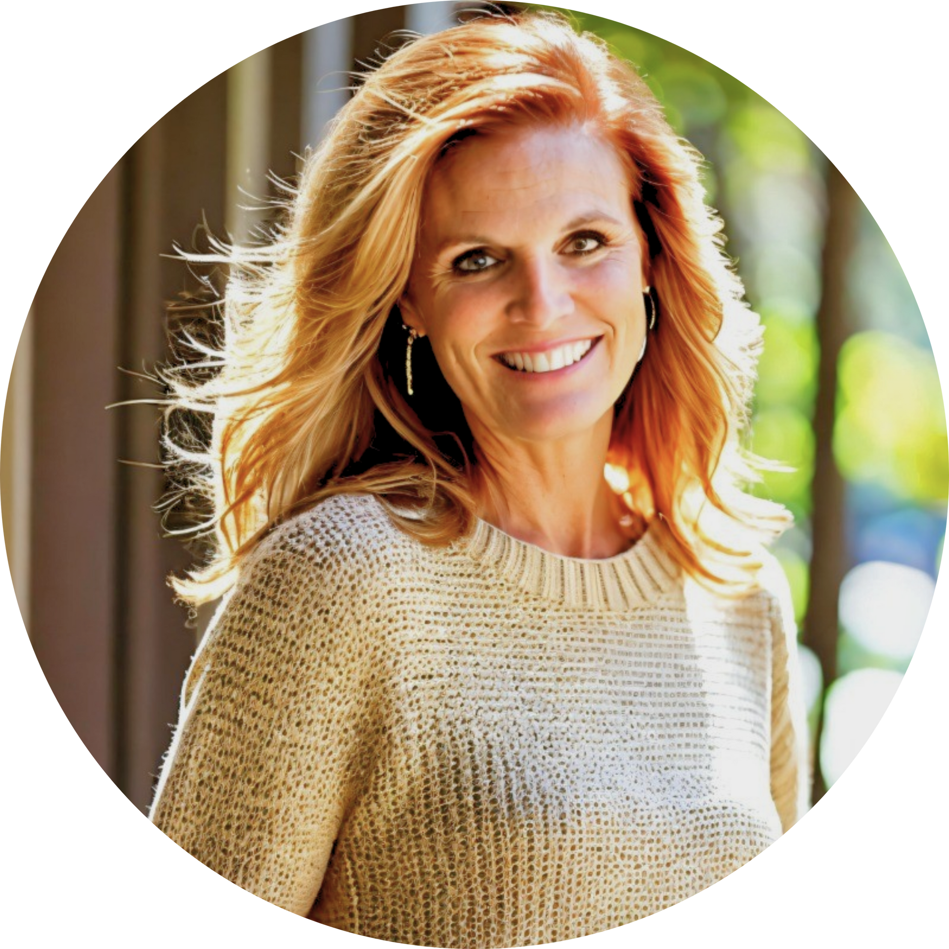 Woman with red hair, smiling in a beige sweater, outdoors with sunlight and foliage.