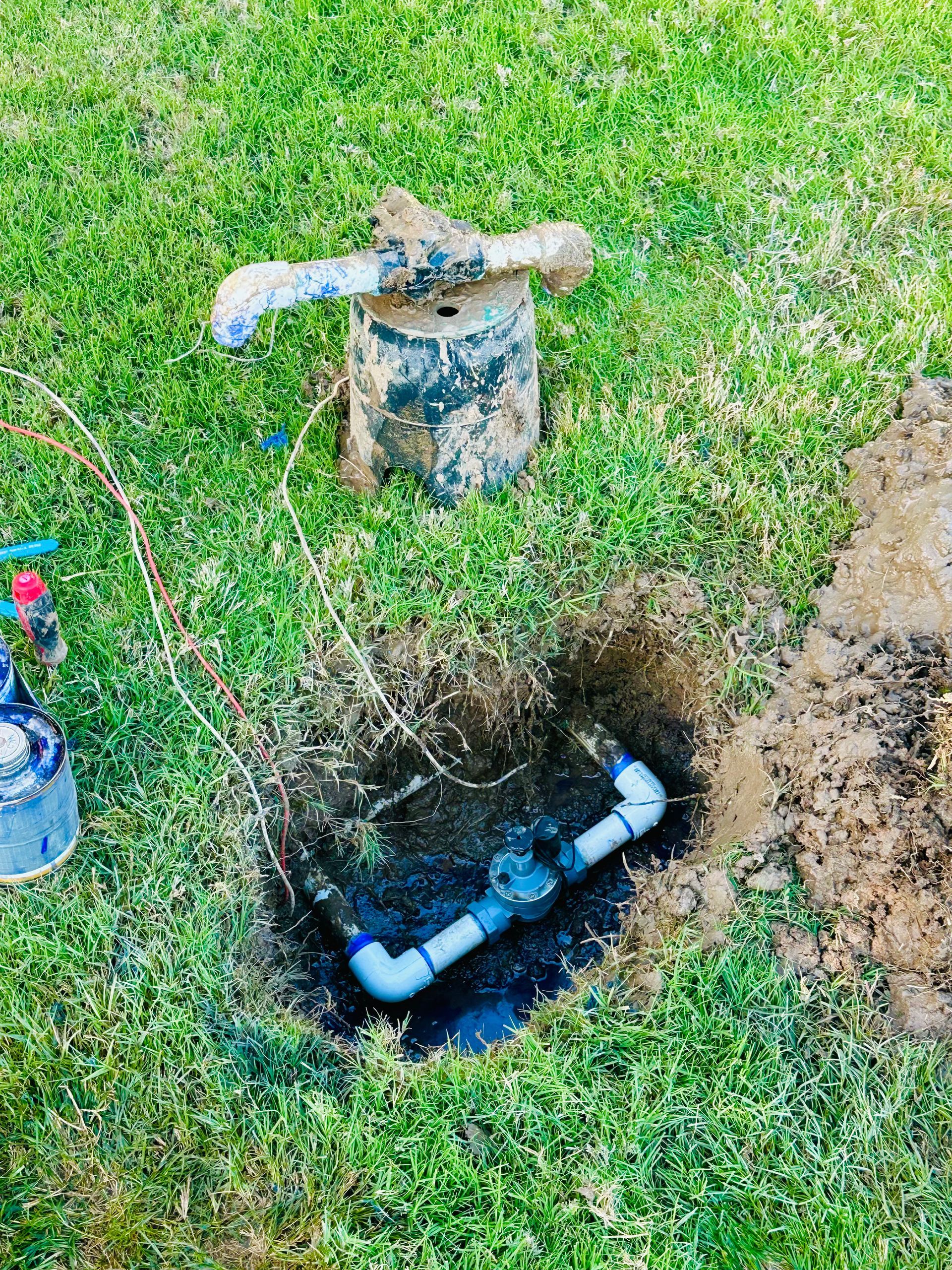A sprinkler is being installed in a hole in the grass.
