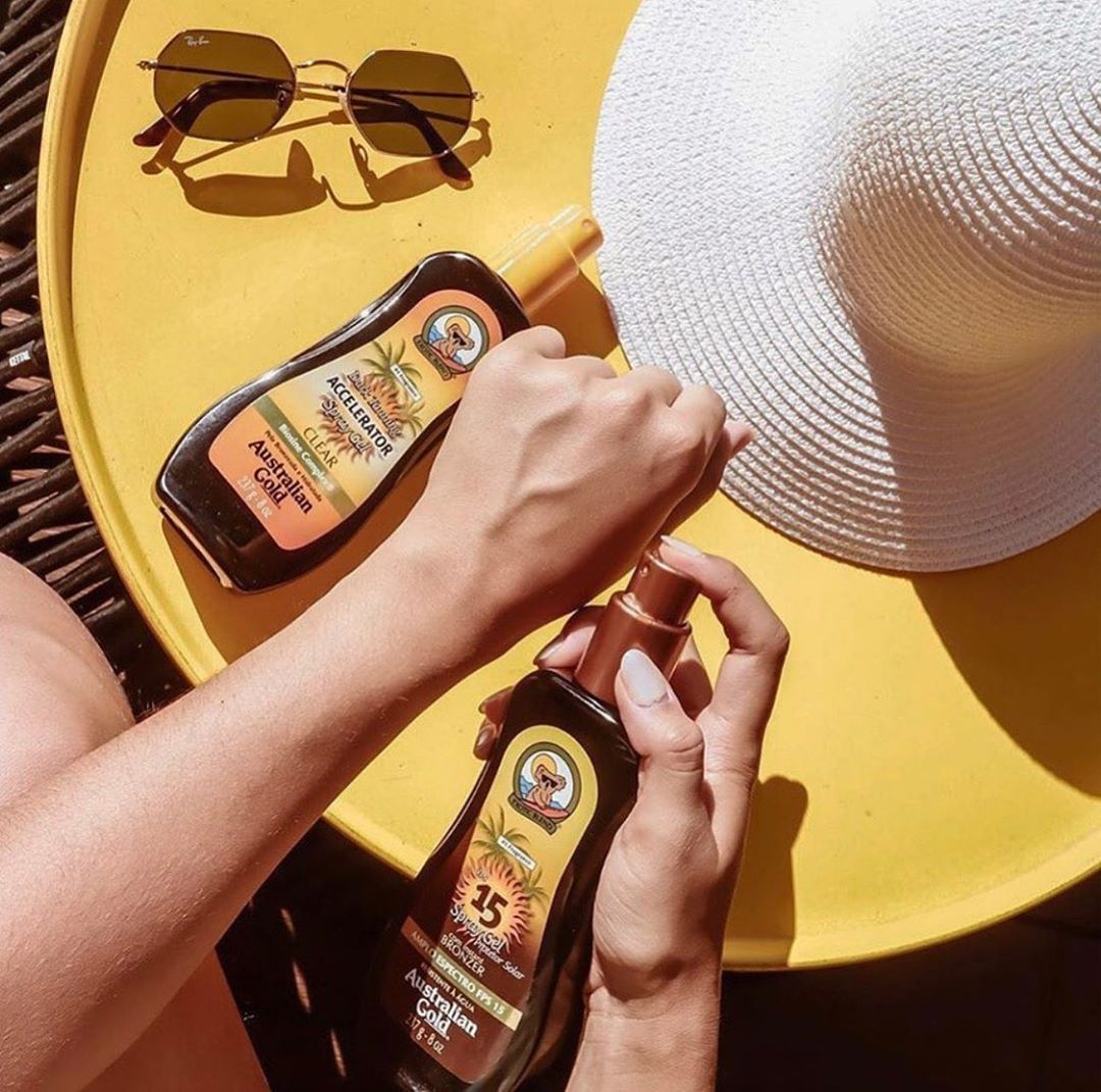 Una persona tiene in mano una bottiglia di crema solare su un tavolo