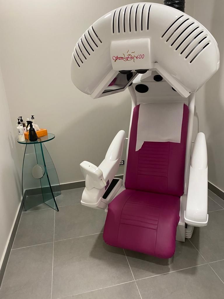 Una sedia rosa e bianca è posta in una stanza accanto a un tavolo.