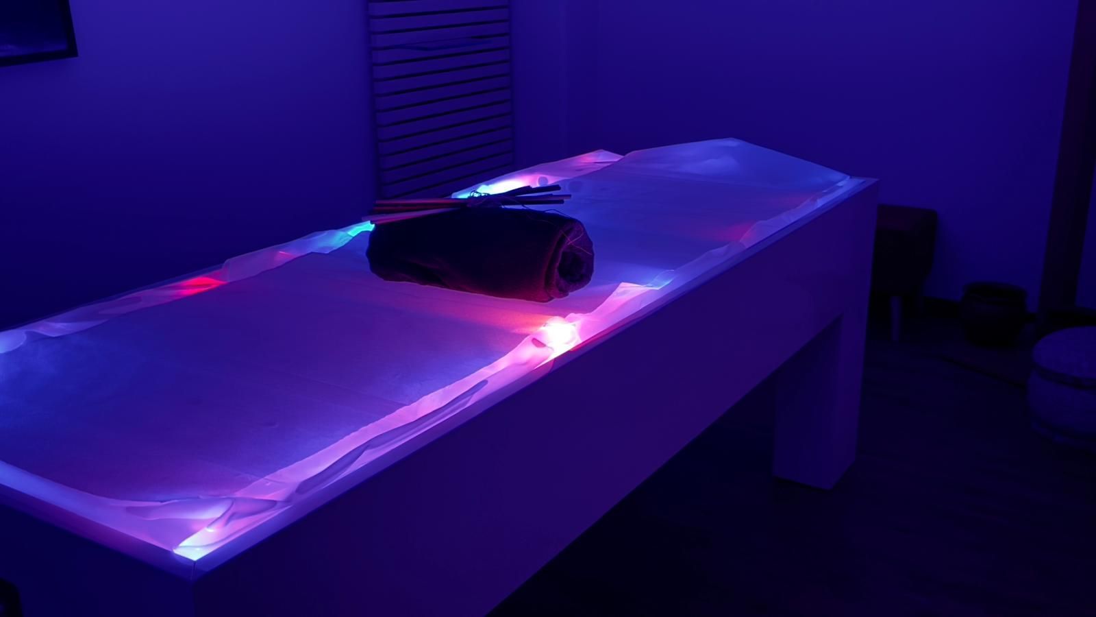 Una vasca da bagno è illuminata da luci viola in una stanza buia.
