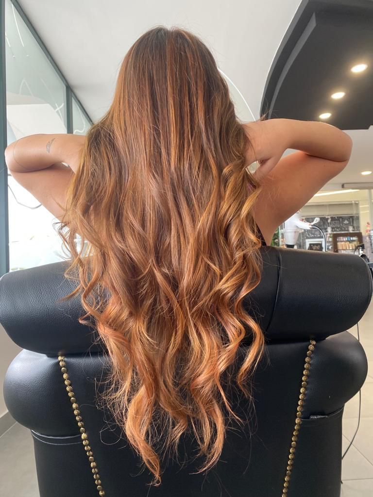 Una donna con i capelli lunghi è seduta su una sedia con le mani dietro la testa.