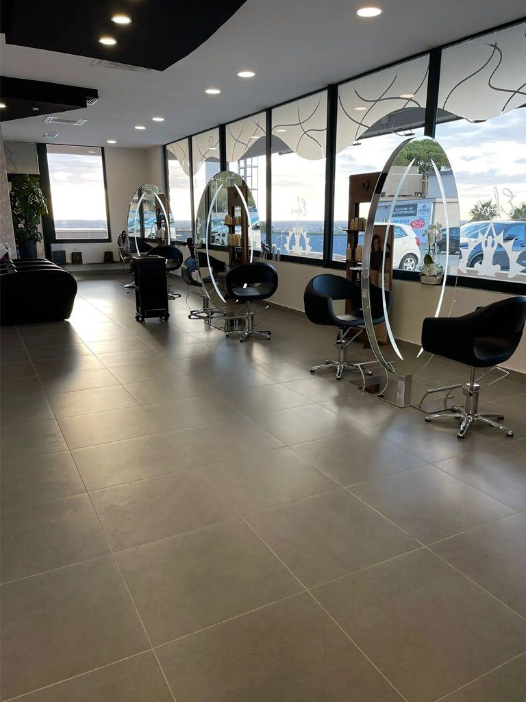 Una grande stanza con tante sedie e specchi in un salone da parrucchiere.