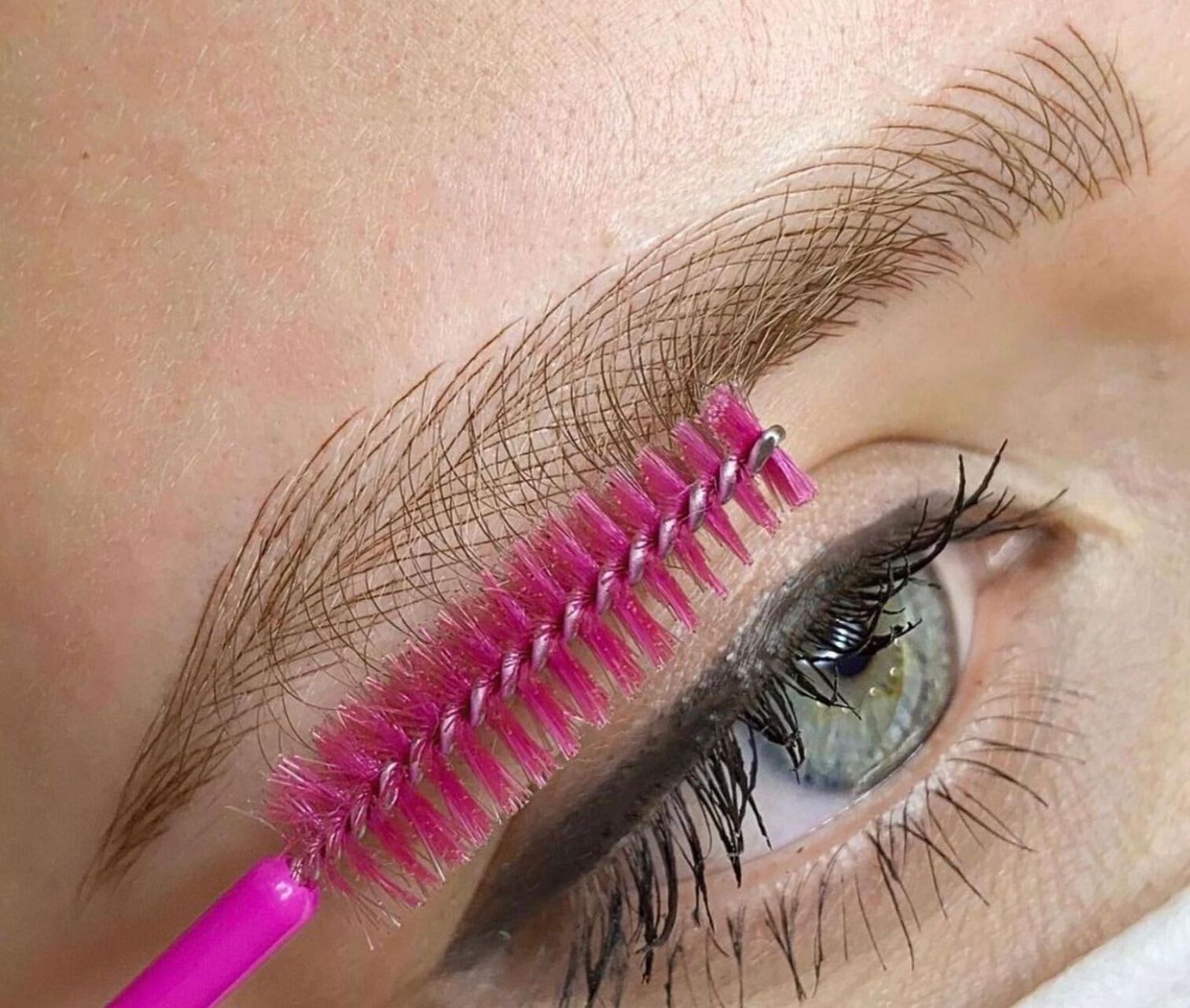 Un primo piano dell'occhio di una donna con un pennello rosa sopra.