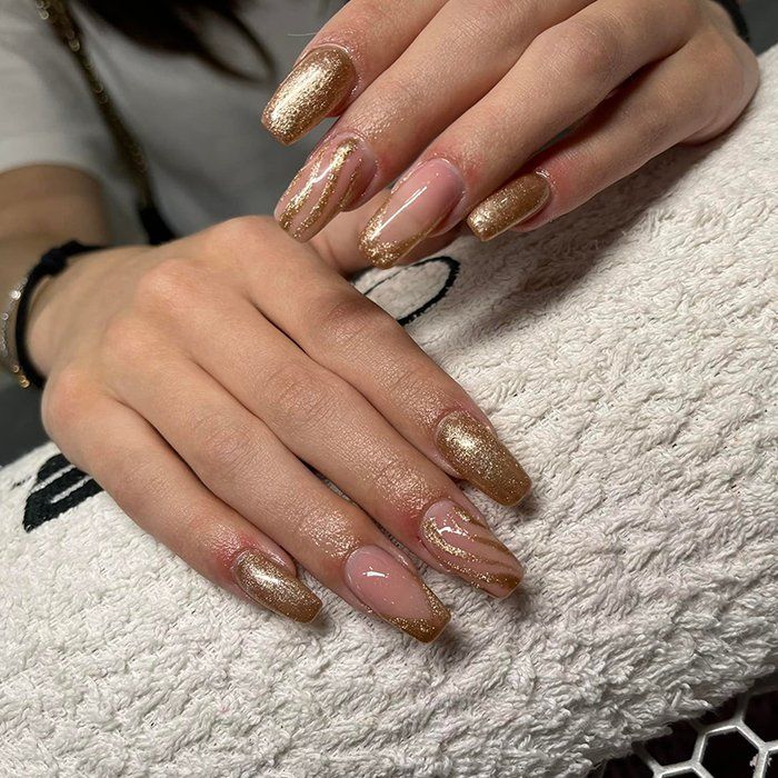 Un primo piano delle mani di una donna con le unghie dorate su un asciugamano.