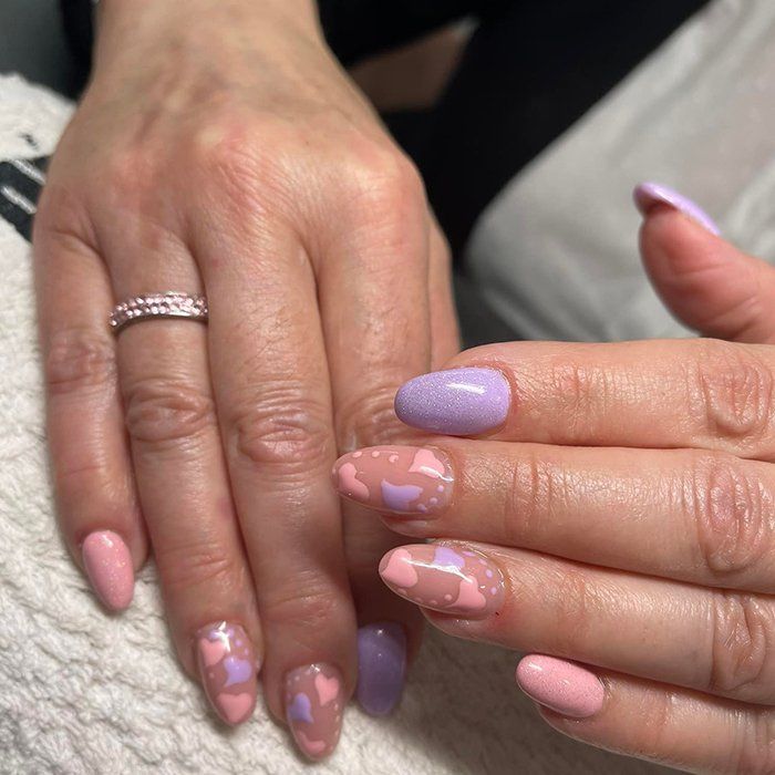 Un primo piano delle mani di una donna con unghie rosa e viola.