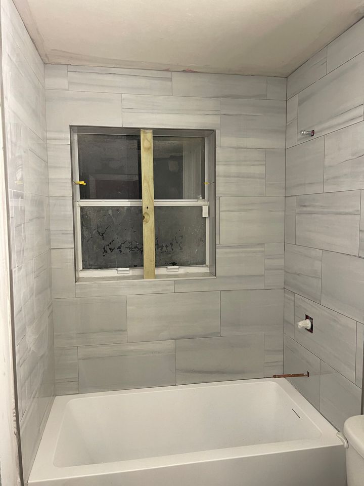 A bathroom with a tub , toilet and window.