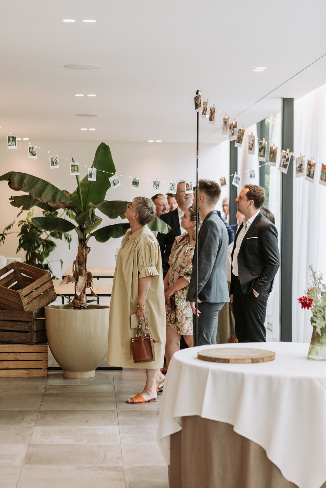 Een groep mensen staat rond tafels in de galerij in feestzaal.