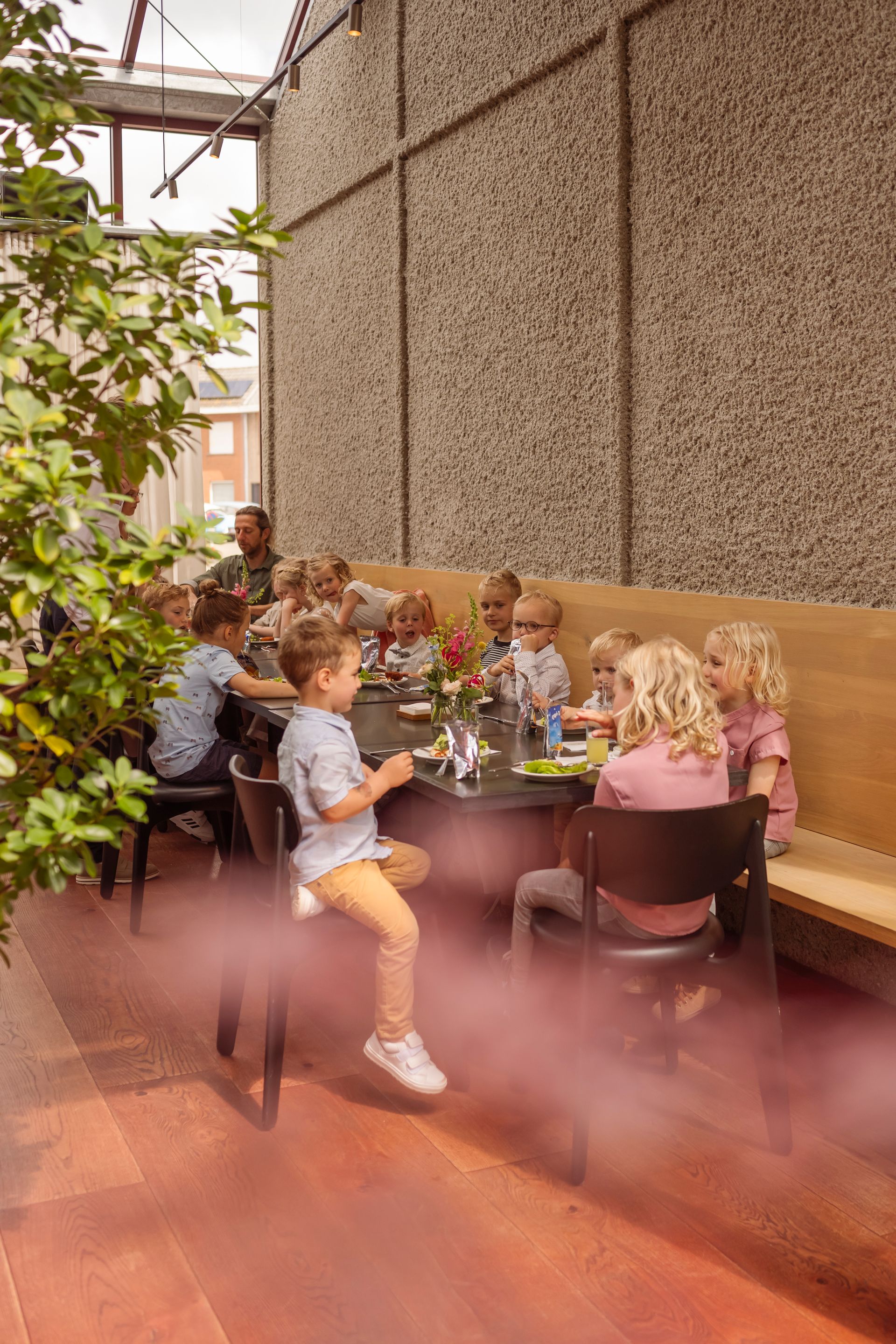 Een groep kinderen zit aan tafeltjes tijdens een lentefeest bij feestzaal t'Hoornaerts in Kachtem, Izegem.