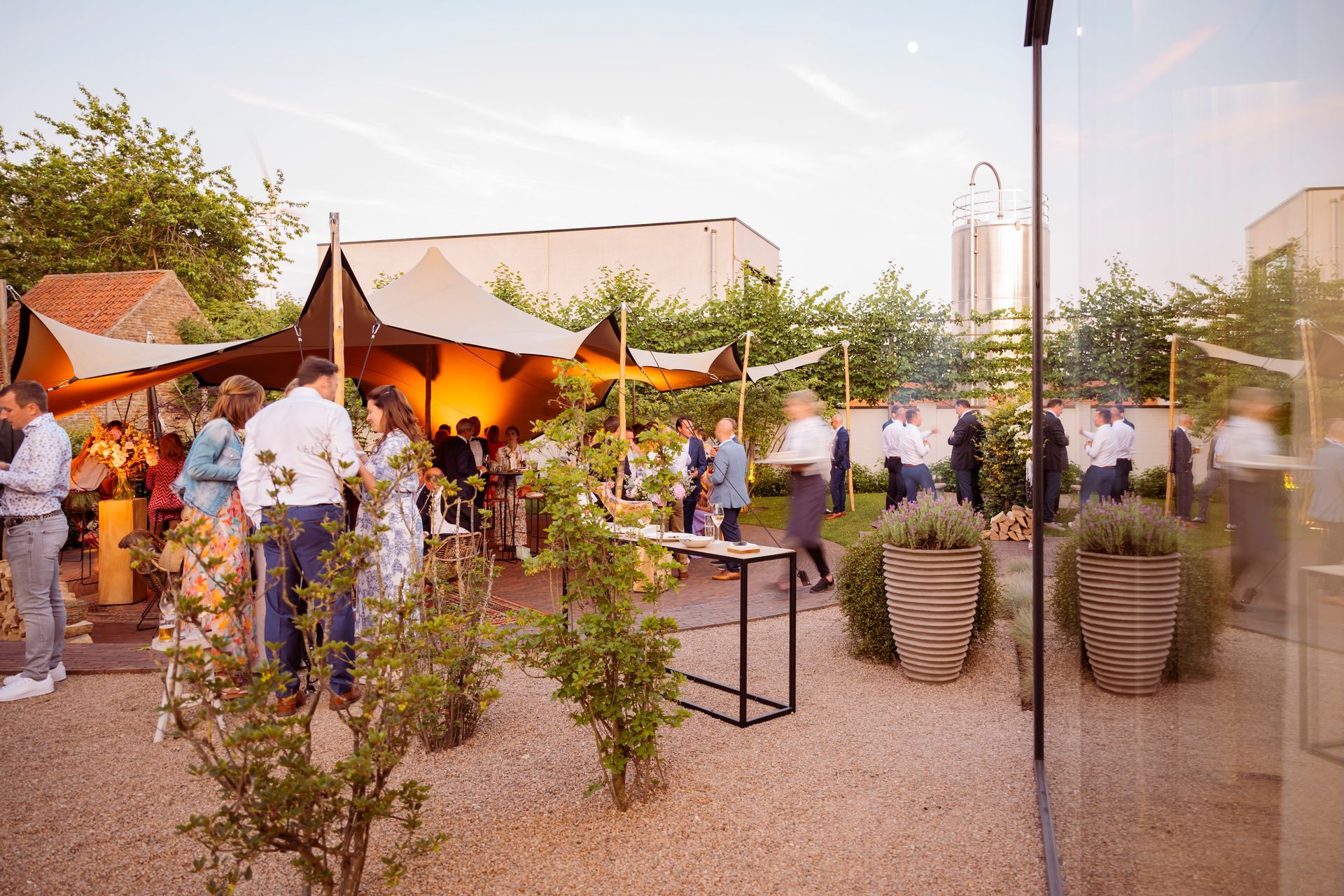 Een groep mensen staat rond een tafel in een tuin.