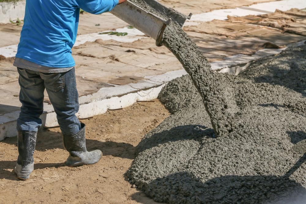 A Man Is Pouring Concrete Into A Pile Of Dirt — Dubbo Mini Mix & Landscape Supplies In Dubbo, NSW