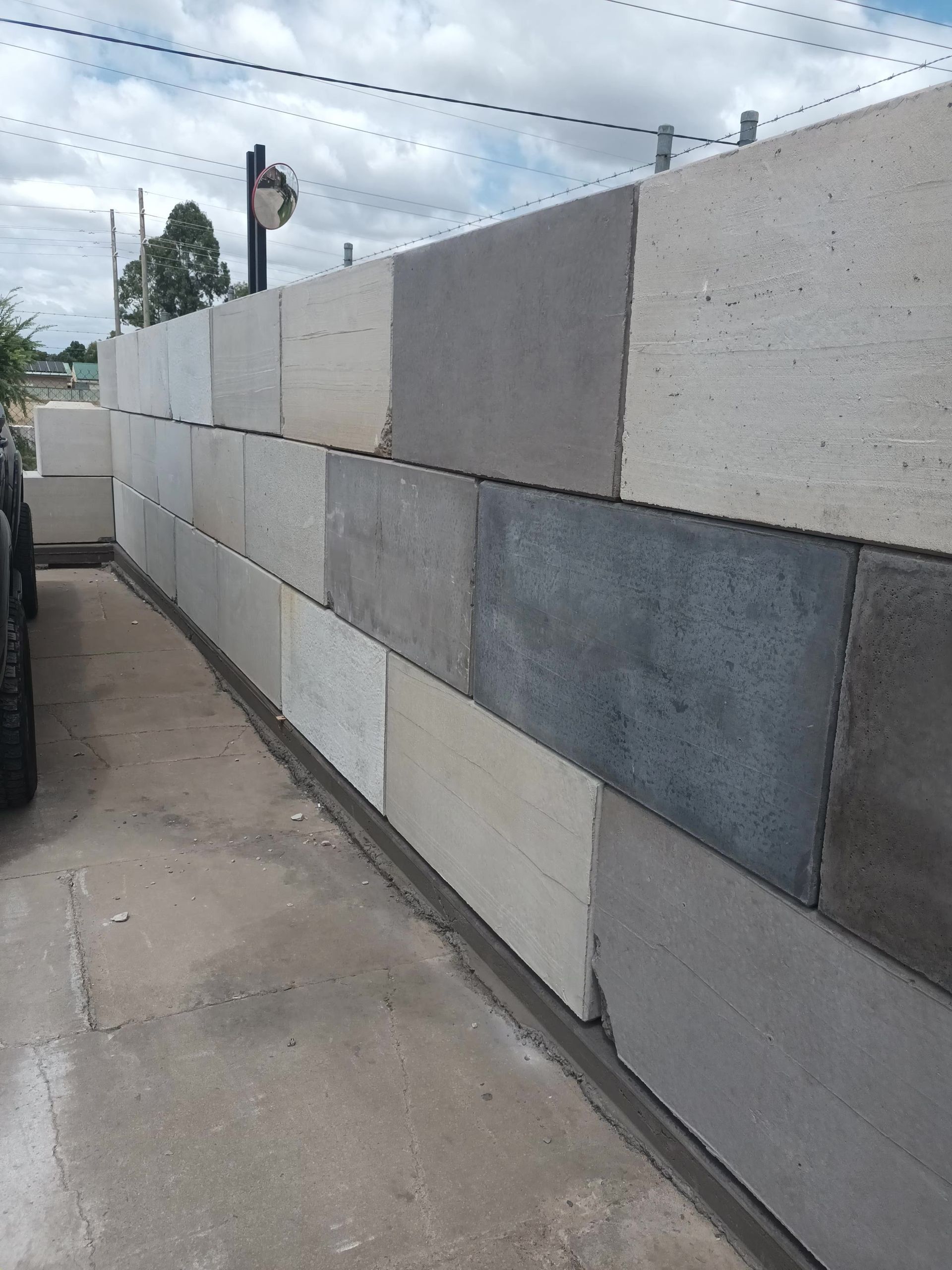 A Stone Wall Along A Sidewalk With Grass In The Background — Dubbo Mini Mix & Landscape Supplies In Dunedoo, NSW