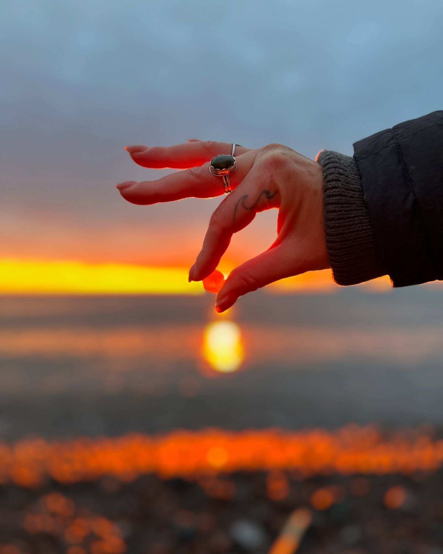 person's fingers holding sea glass at sunrise