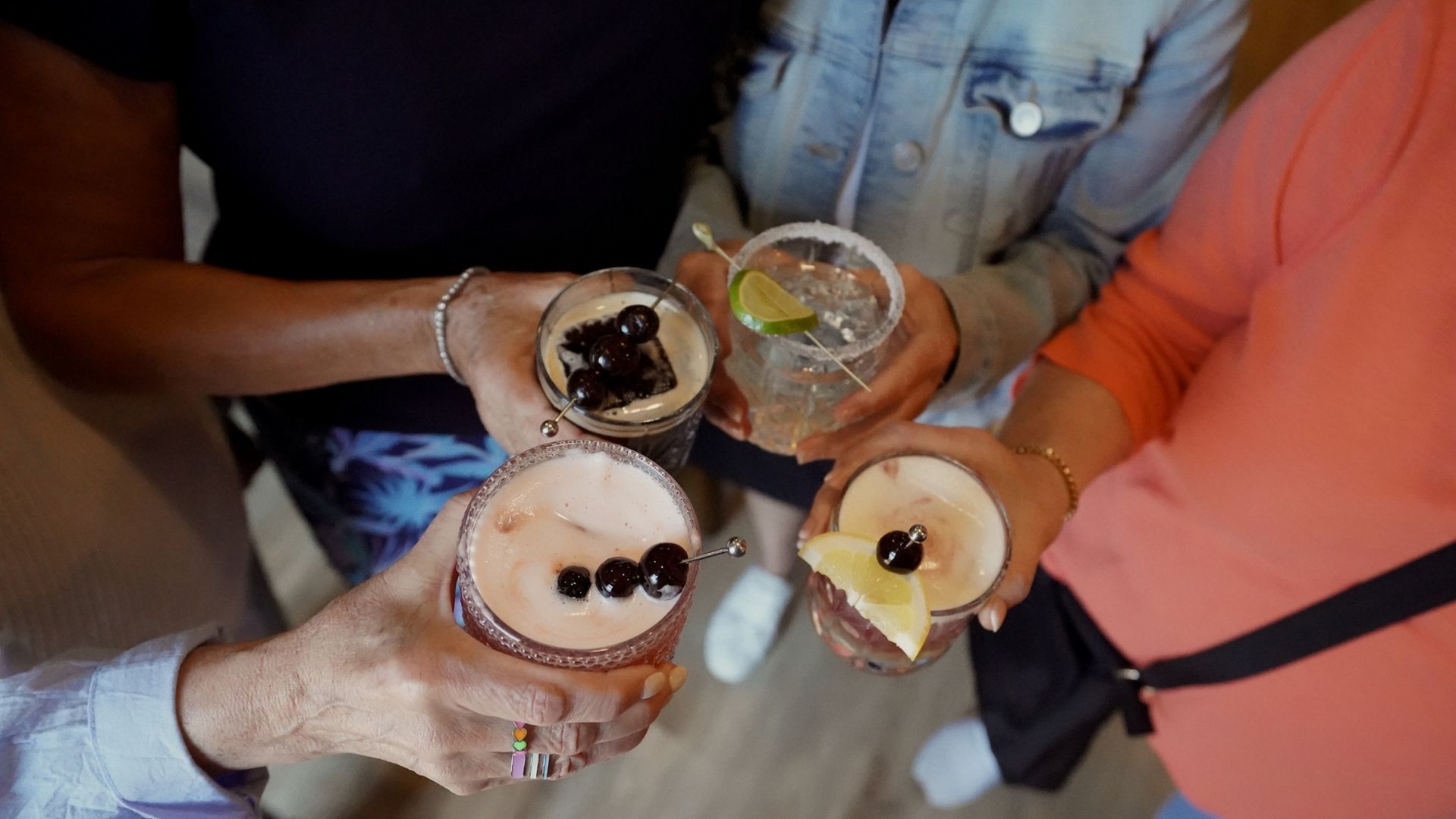 people holding a group of cocktails together