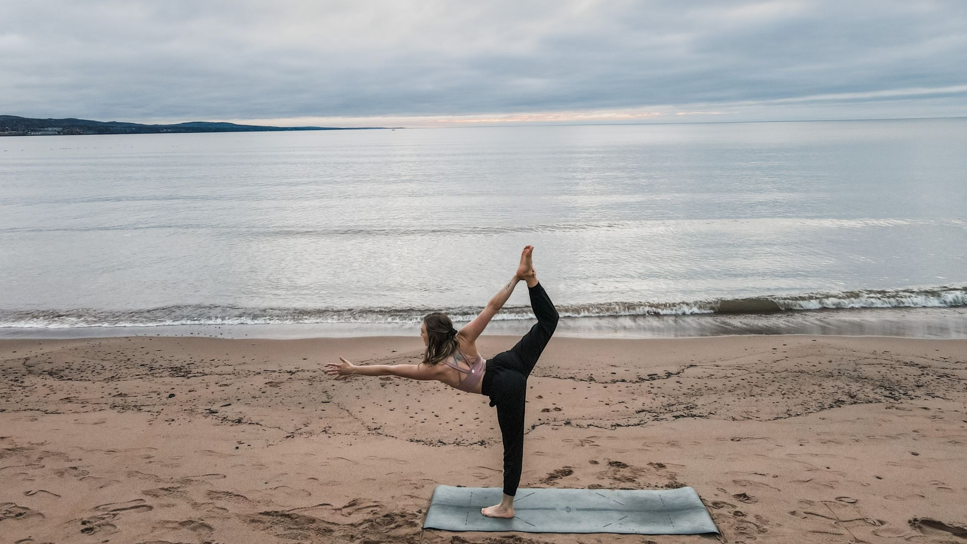 person doing yoga on the beach of lake superior