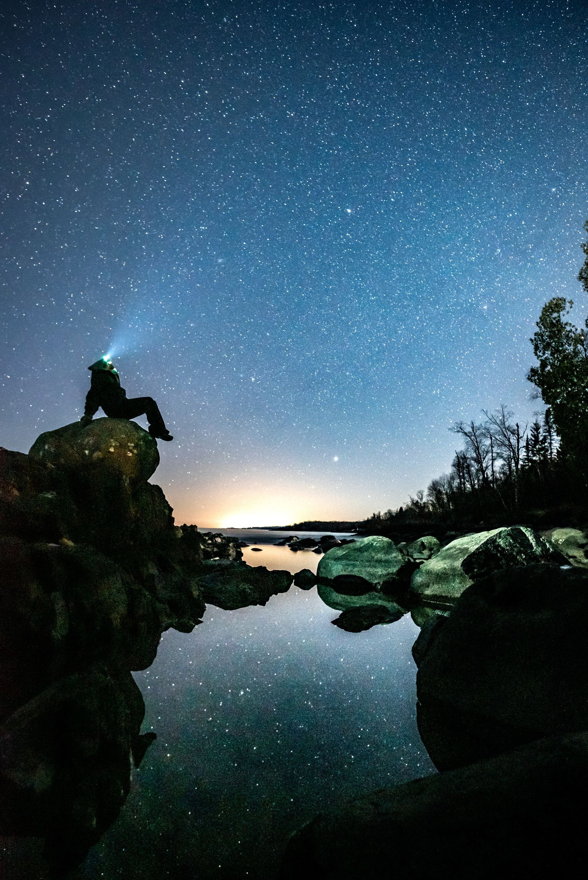 person sitting in the dark with headlamp looking at the stars