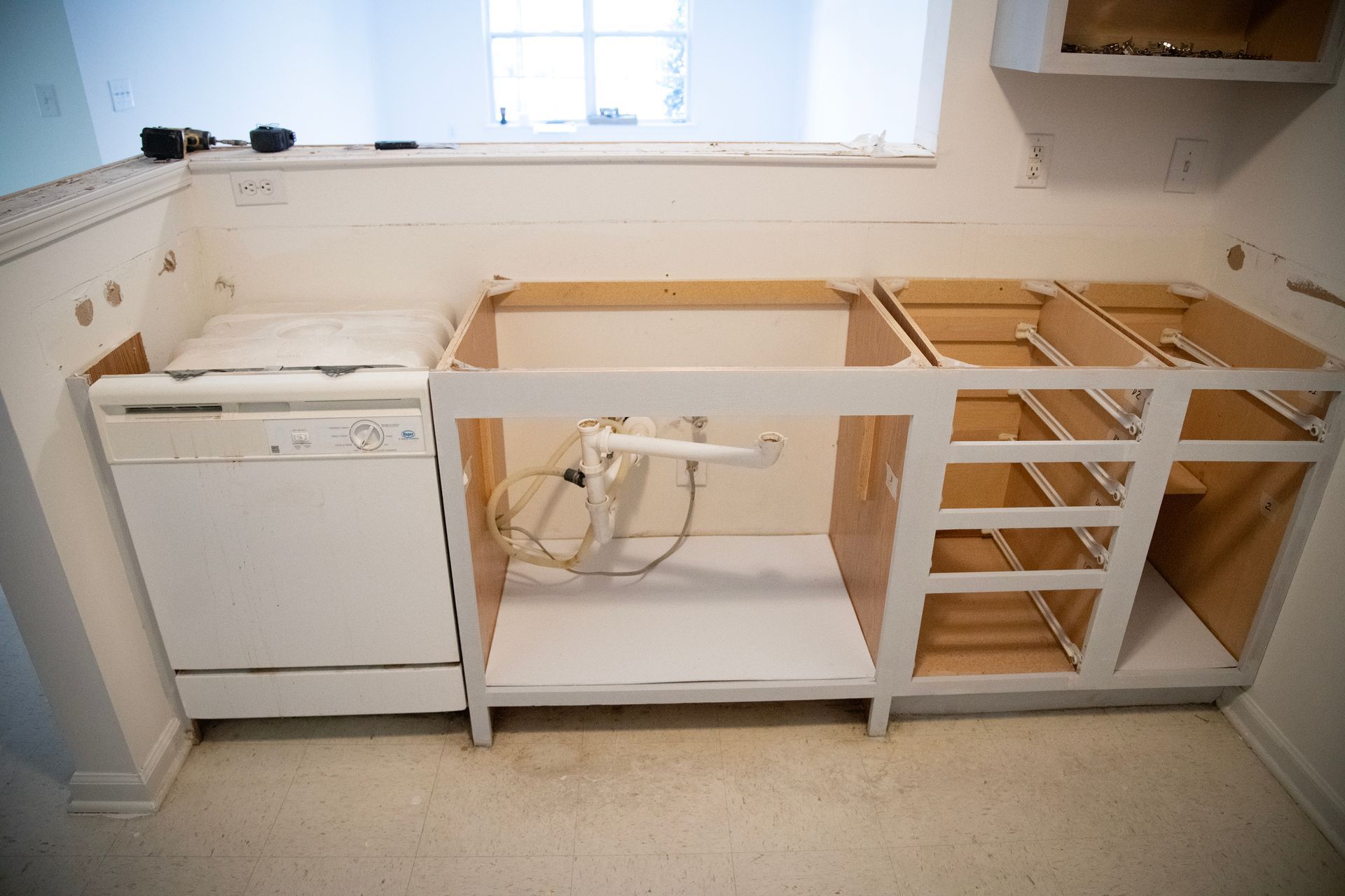 Kitchen with installed dishwasher and unfinished cabinets.