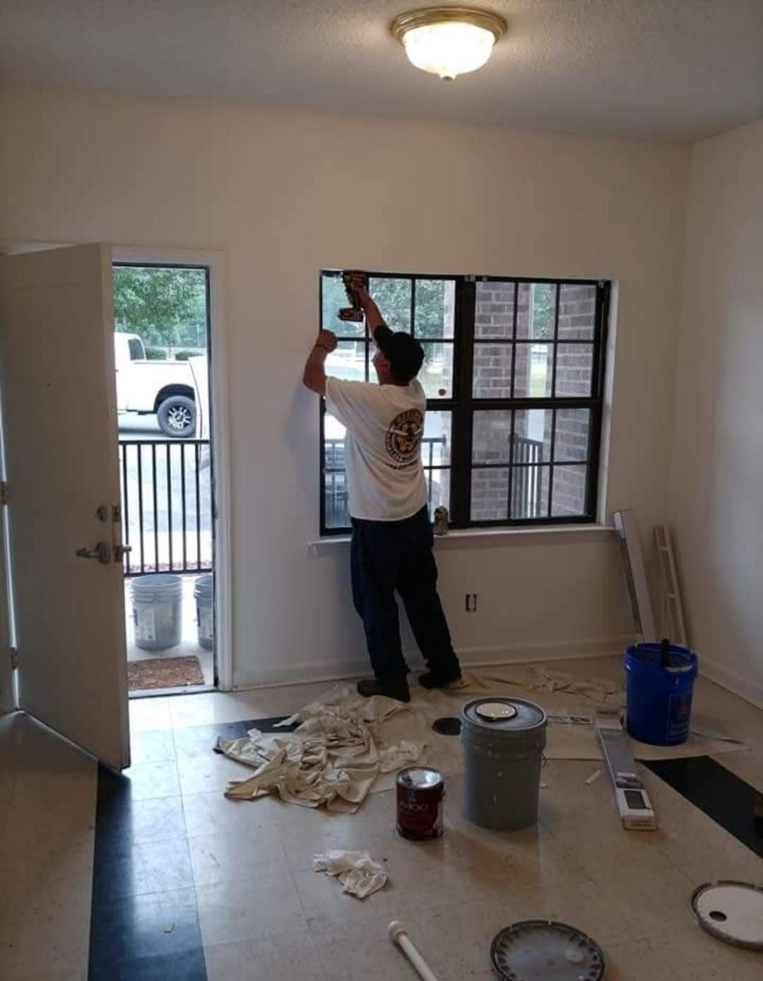 A person installing something near a window inside a room.