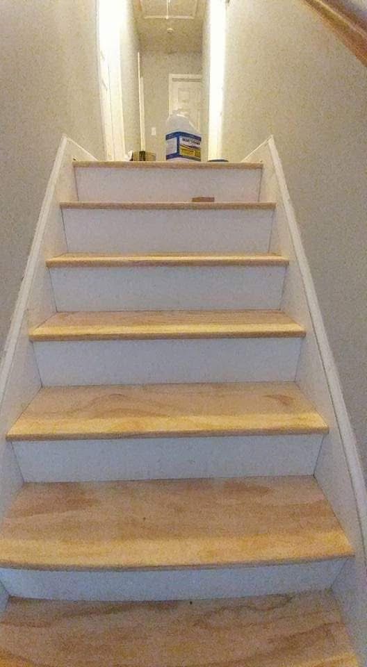 Staircase with light-colored wooden steps and white risers, leading upwards.