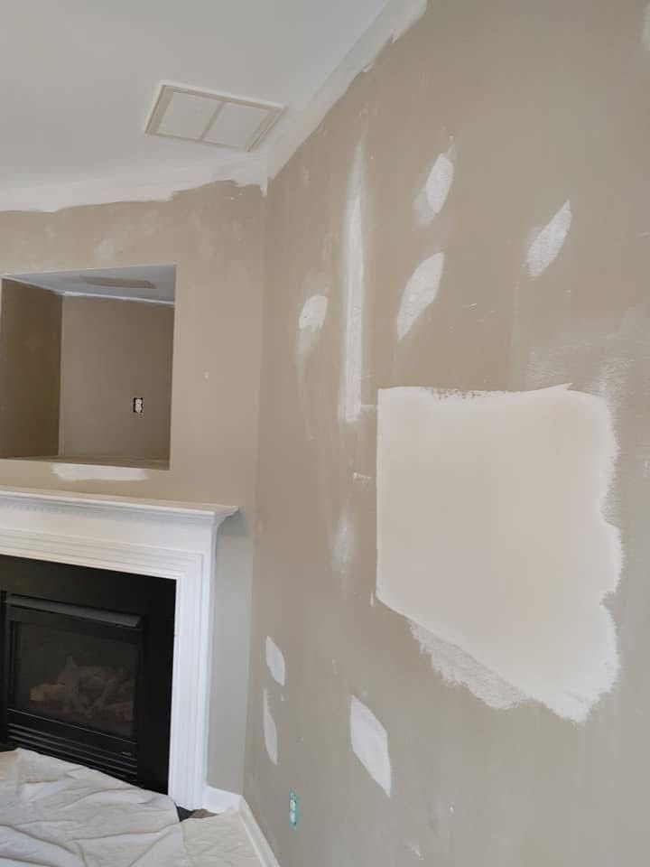 Interior wall with patches of drywall compound, near a fireplace and recessed area.